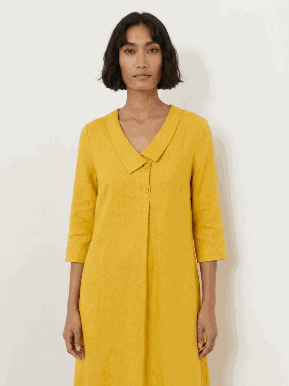 Woman wearing navy linen-look midi dress with blazer-inspired neckline and button detail, standing outdoors