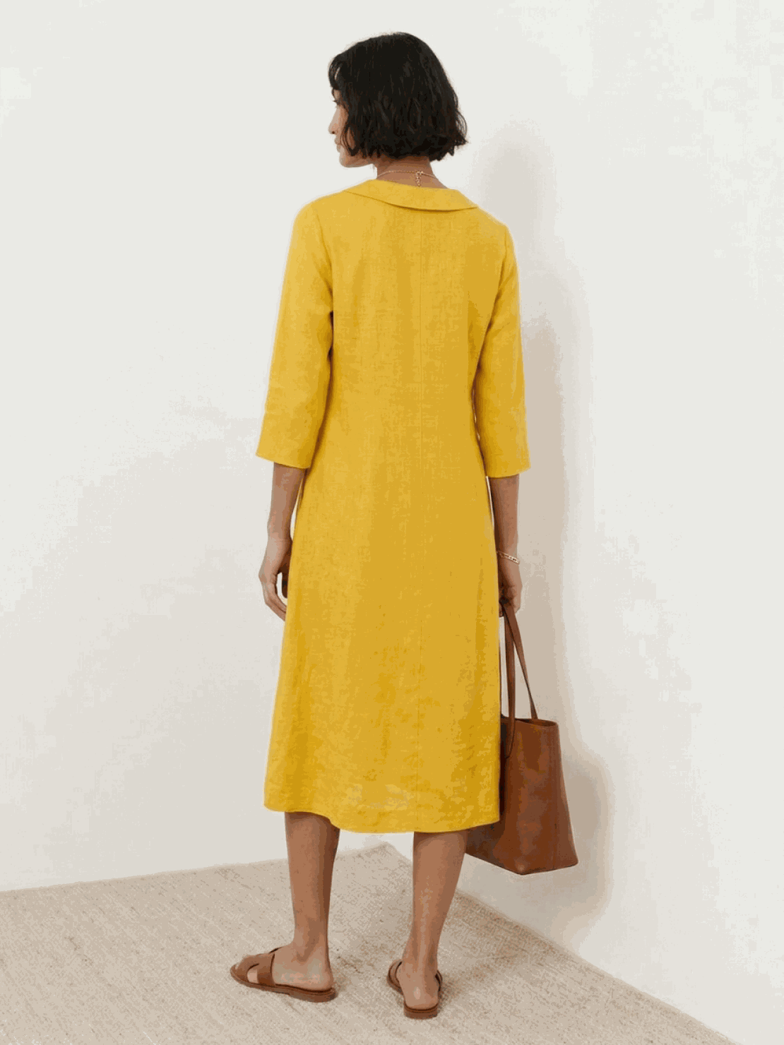Woman wearing navy linen-look midi dress with relaxed A-line silhouette and button detail standing outdoors