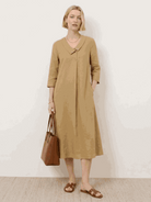 Woman wearing navy linen-look midi dress with relaxed fit and blazer-inspired neckline outdoors