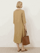 Woman wearing navy linen-look midi dress with relaxed fit, V-neckline, two-button chest detail, 3/4 sleeves, and side pockets.