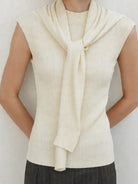 Beige knit vest with attached scarf in fine ribbed knit, sleeveless design, and mock neckline.