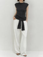 Beige knit vest with attached scarf in fine ribbed knit, sleeveless with mock neckline, styled on model