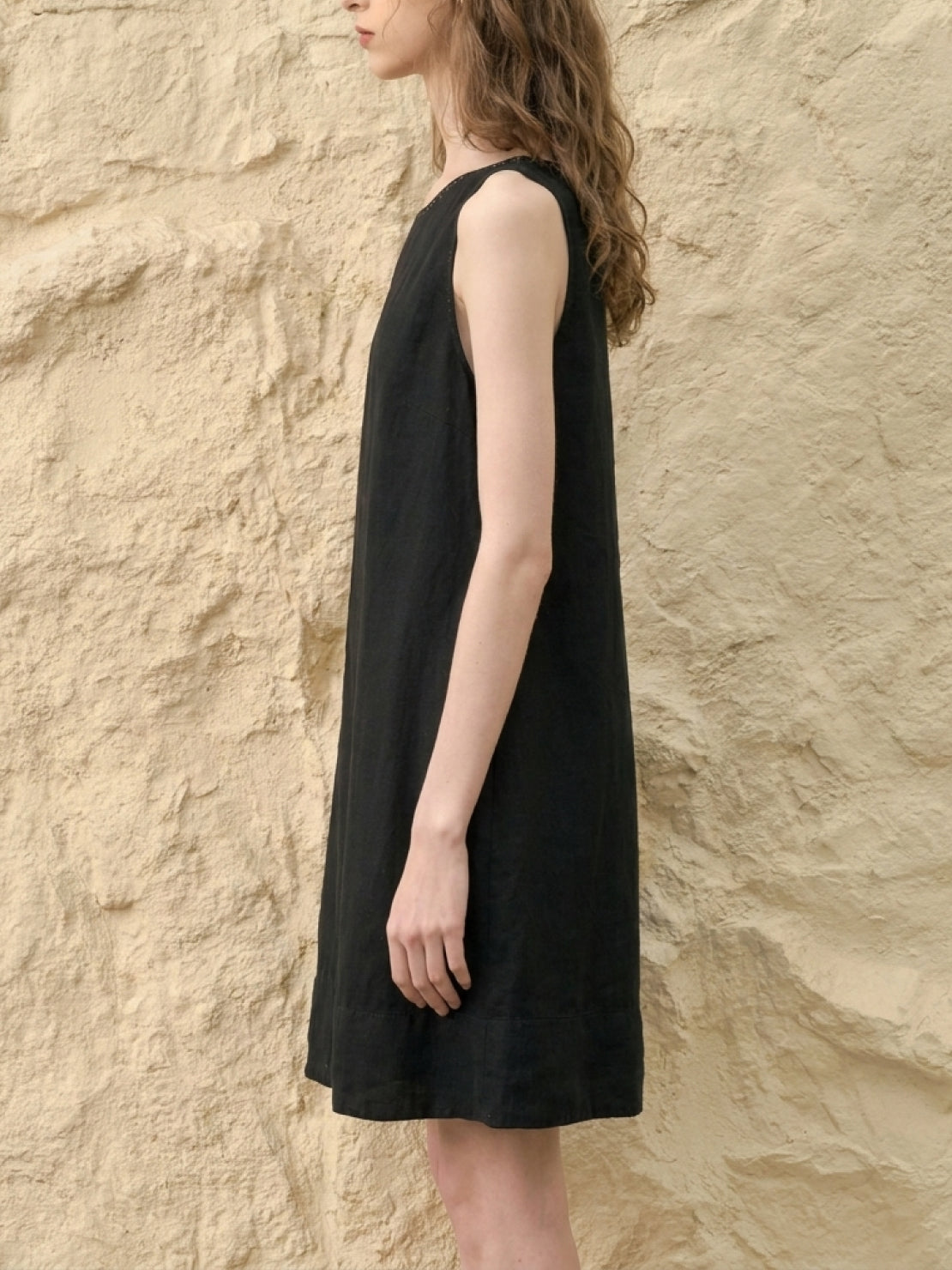 woman wearing sleeveless relaxed linen lyocell blend dress with hand-stitched neckline detail
