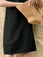 Woman wearing a sleeveless linen Lyocell blend shift dress with a relaxed A-line silhouette and round neckline