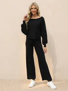 Woman wearing black round neck loose fit cozy two-piece set with wide-leg pants and white sneakers