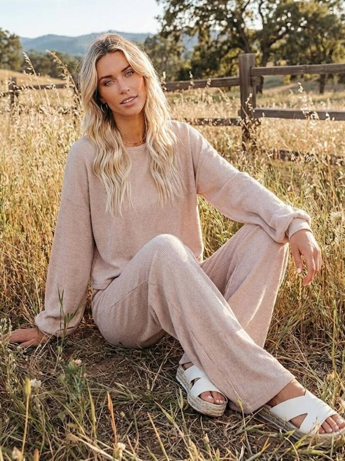 Woman wearing beige round neck loose fit cozy two-piece set sitting outdoors on grass
