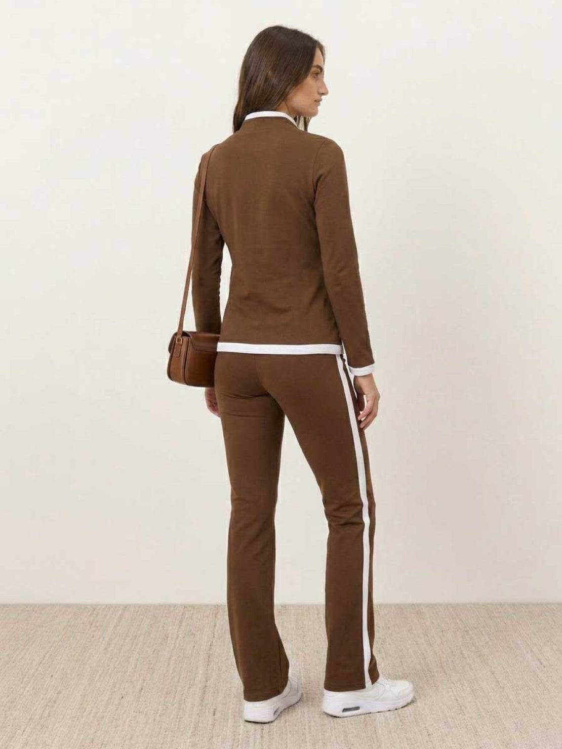 Woman wearing sleek black contrast zip two-piece outfit with fitted top and pants on white background