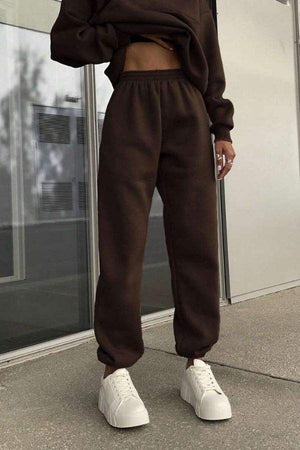 woman wearing dark brown joggers and matching pullover sweatshirt with white platform sneakers in urban setting classic airplane set