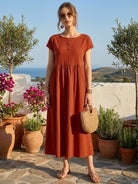 Woman wearing a capped-sleeve voluminous pleated midi dress with flowing fabric and pockets