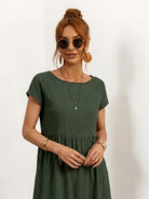 Woman wearing capped-sleeve voluminous pleated midi dress with flowing skirt and pockets