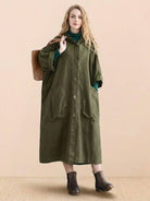 Woman wearing oversized olive green waterproof design windbreaker jacket with large pockets and attached hood