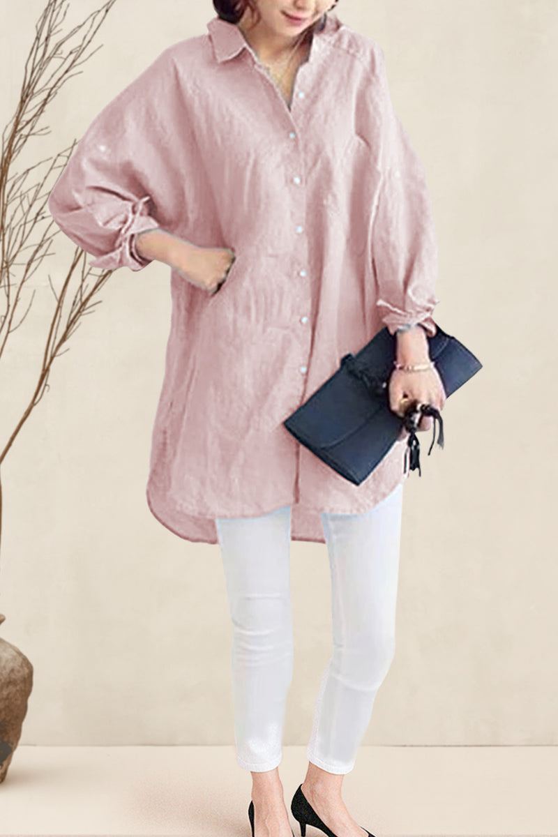 Woman wearing oversized linen shirt in sun-washed pink with loose sleeves and flowing hem paired with white pants and black clutch