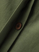 Close-up of oversized 100% cotton shirt fabric and button in olive green color