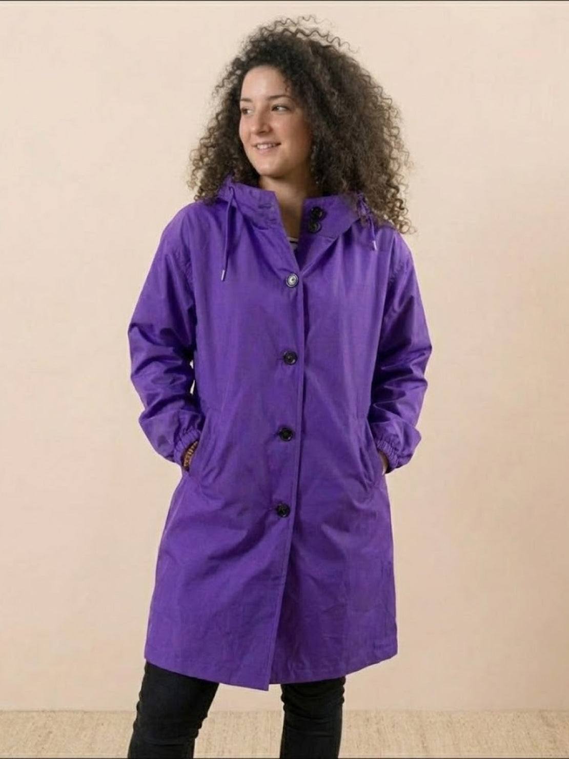 Woman wearing purple Rain Couture Windbreaker oversized water-resistant jacket with hood and pockets