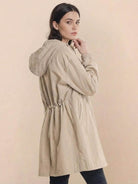 Woman wearing beige oversized Rain Couture Windbreaker with hood and adjustable waist
