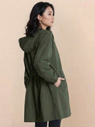 Woman wearing oversized olive green Rain Couture Windbreaker windproof and water-resistant jacket with hood and pockets