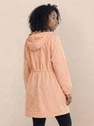 Woman wearing peach oversized Rain Couture Windbreaker with hood and adjustable waist viewed from back