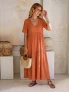 Woman wearing a V-neck two-tiered maxi swing dress in flowing cotton fabric with irregular hemline and loose sleeves
