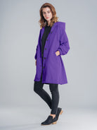 Water-resistant oversized hooded windbreaker rain jacket in black with multiple pockets and adjustable fit.